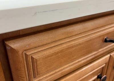 Close-up of a quartz vanity countertop edge with a visible scratch above the cabinet drawer