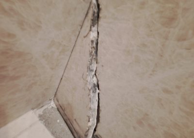 Before photo of a shower wall crack with severe separation and damage near the corner