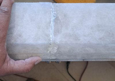 Before photo of a damaged stone seam repair showing visible separation and filler buildup